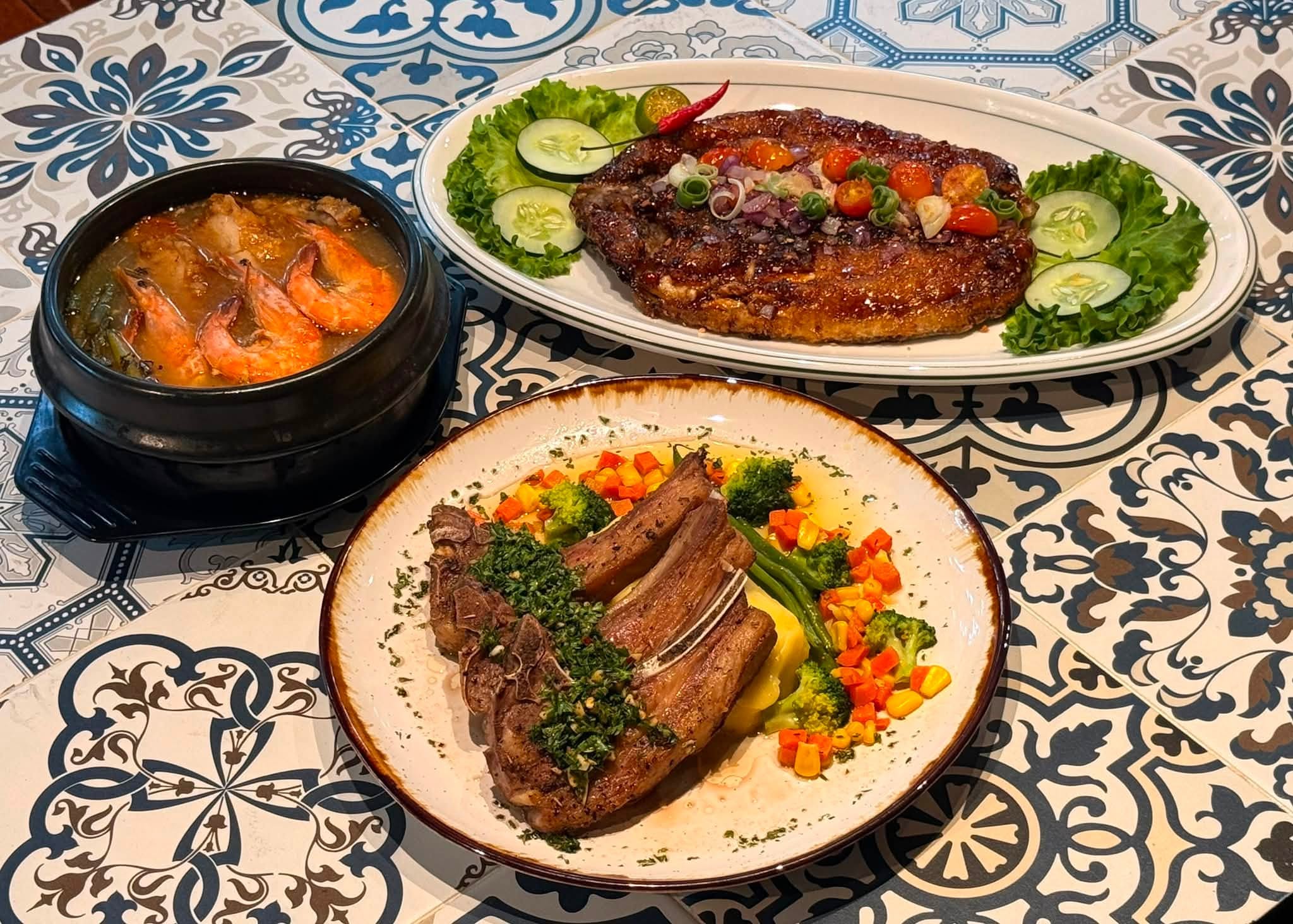 Entrecôte steak, lamb chops with chimichurri and a clay pot of prawns on Spanish tile